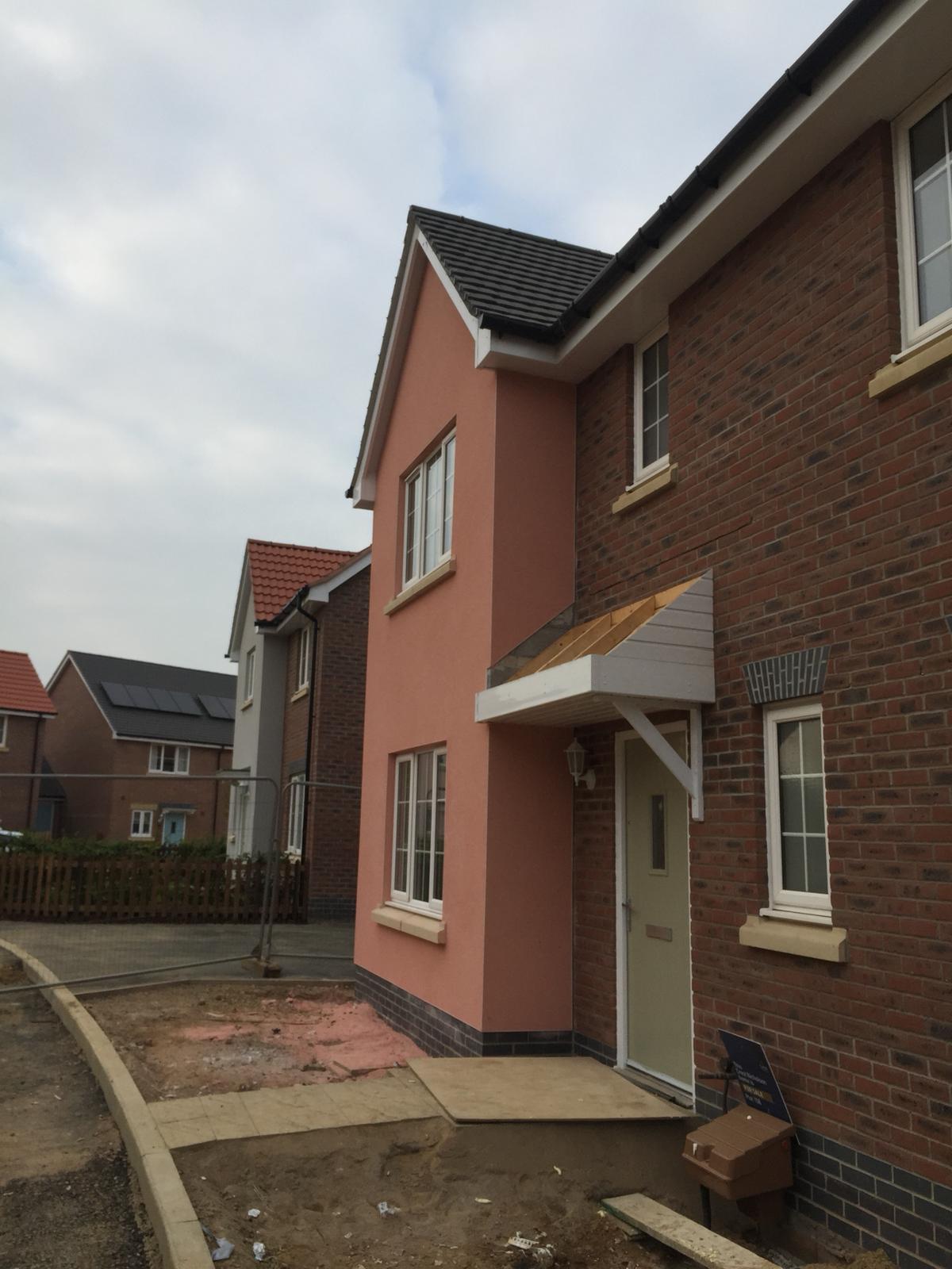 A warm coloured render complements the brickwork of a new home.
