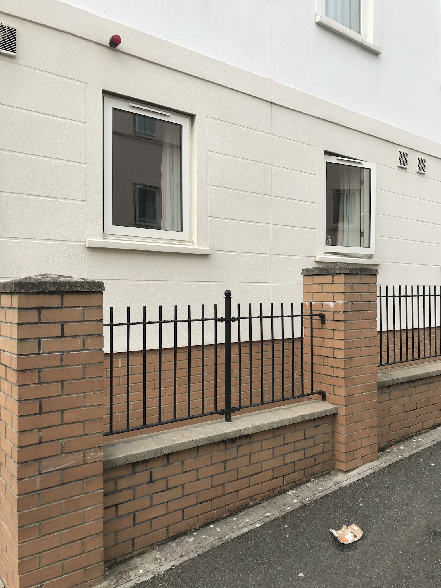 A rendered exterior alongside the property’s brick boundary wall and railings.