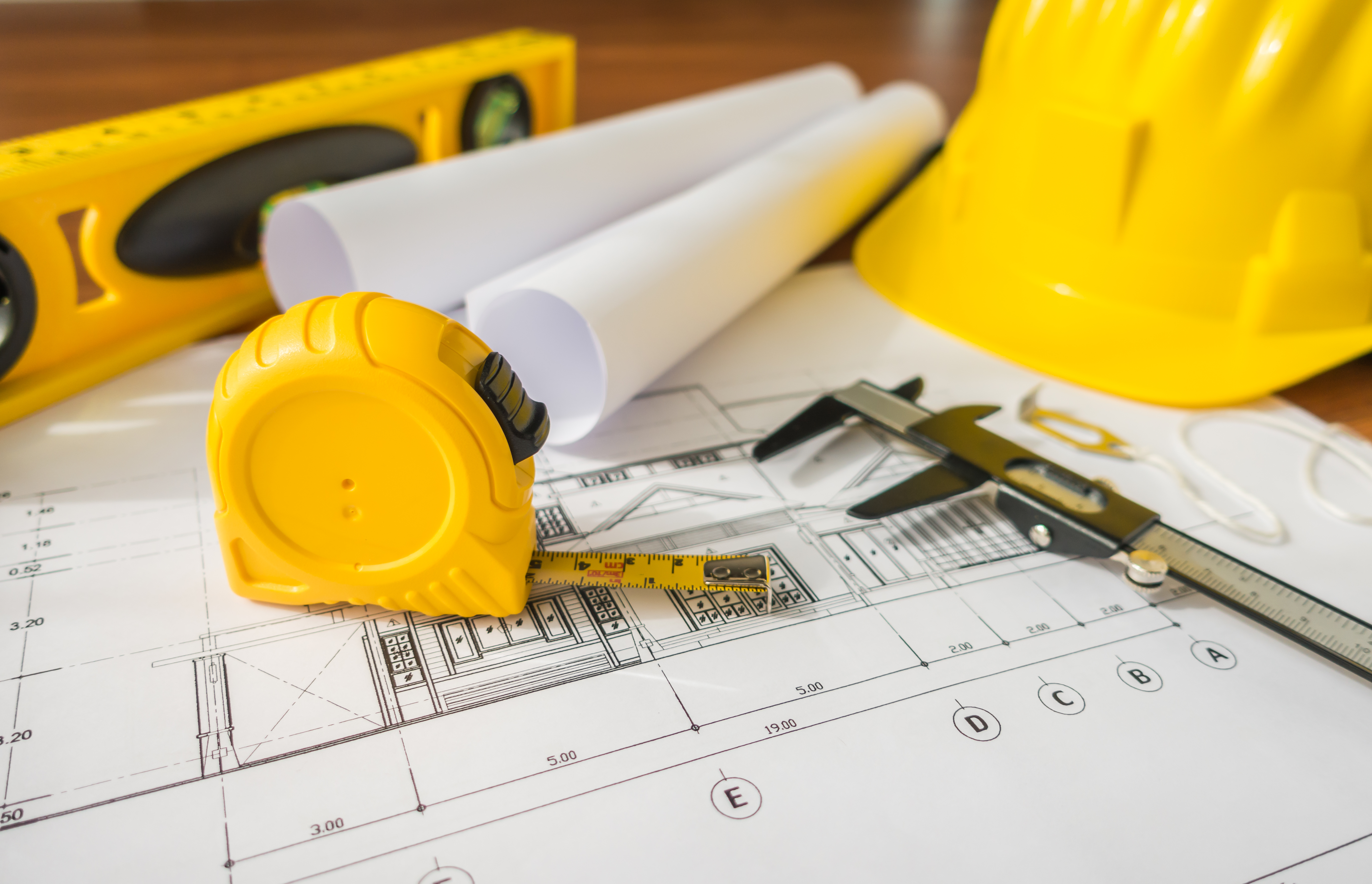 Construction plans with yellow helmet and drawing tools on bluep Construction plans with yellow helmet and drawing tools on blueprints